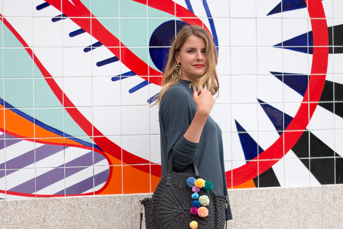 Woman in front of vibrant mural.