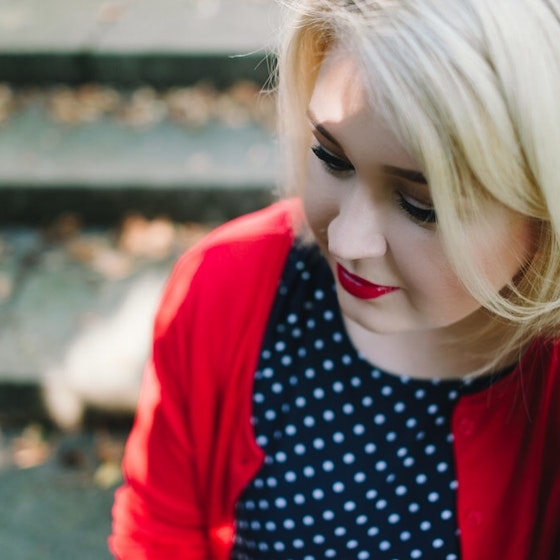 Blonde woman with red lipstick and red cardigan.