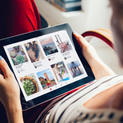 Woman holding tablet with Pinterest app.