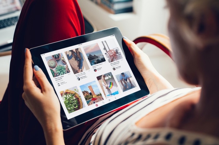 Woman holding tablet with Pinterest app.